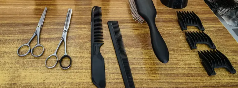 Gunting, sisir, dan sikat pangkas tertata di meja kayu